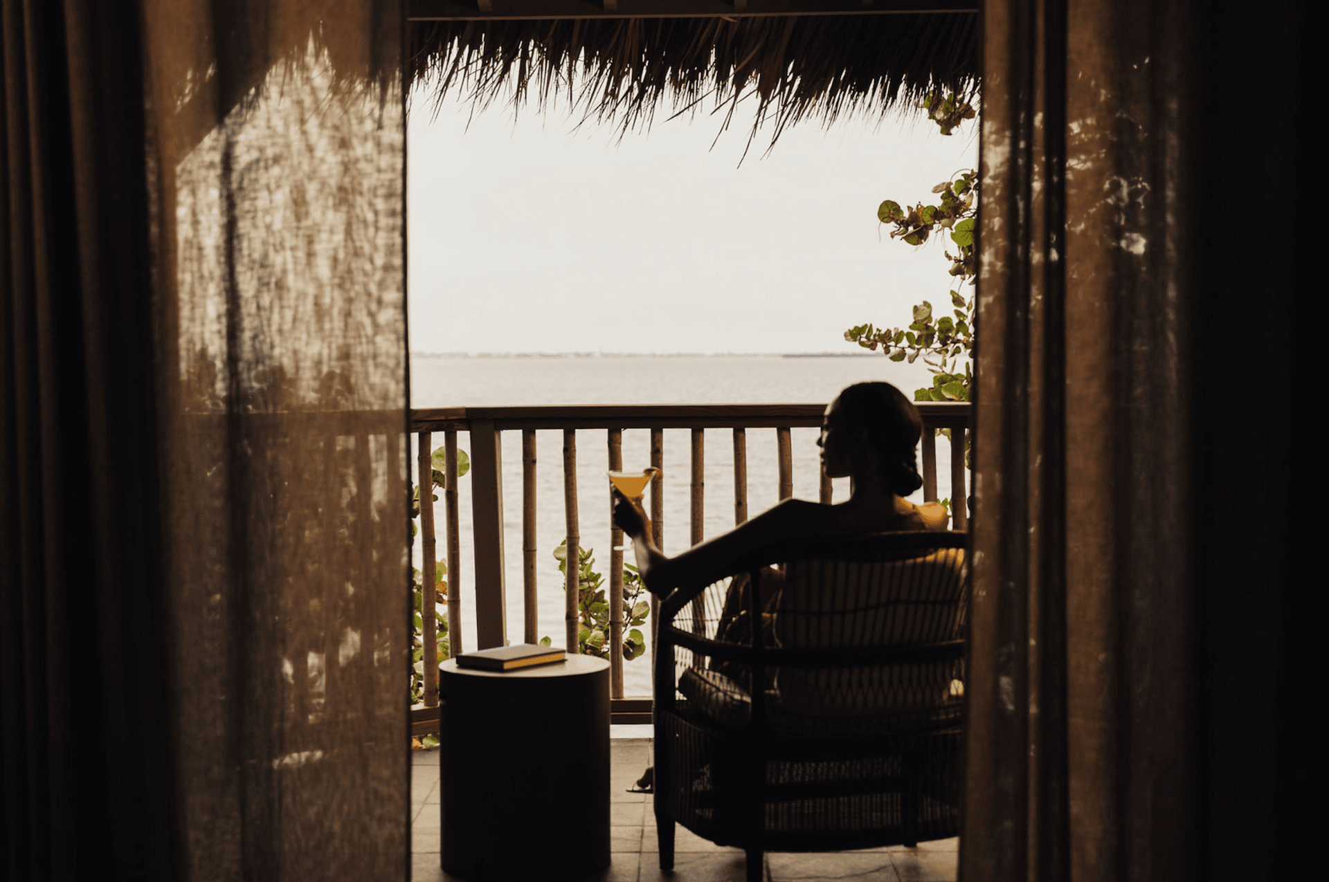 Woman enjoying a drink on her balcony at a Noble House Hotels & Resorts property