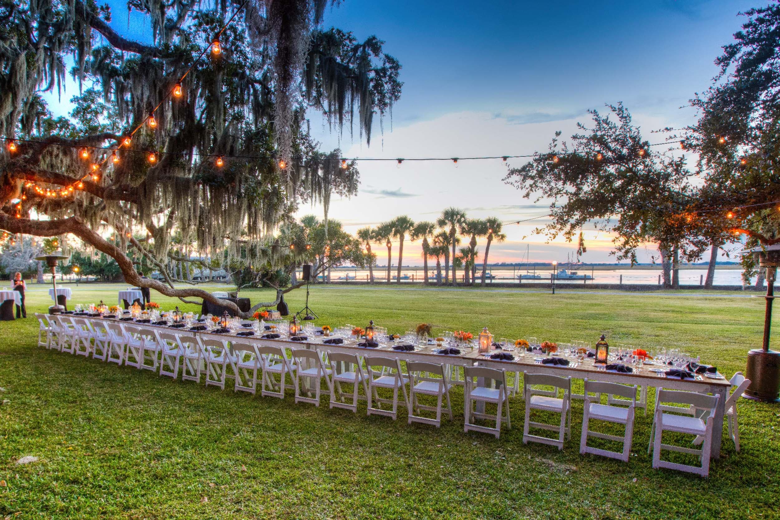 Long table setting on the grass in front of the water at a Noble House Hotels & Resorts property