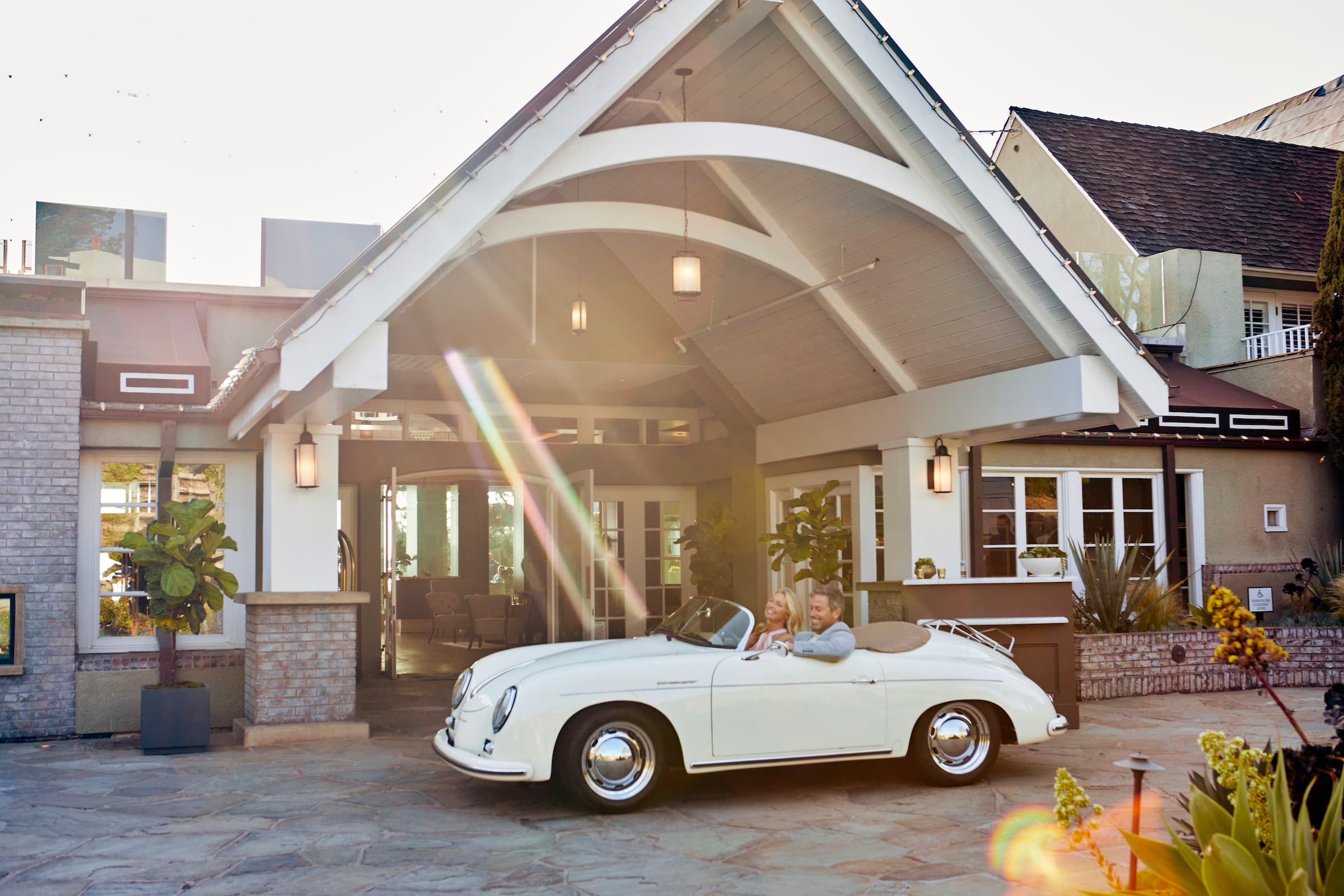 Couple in vintage car parked outside L'Auberge Del Mar in California