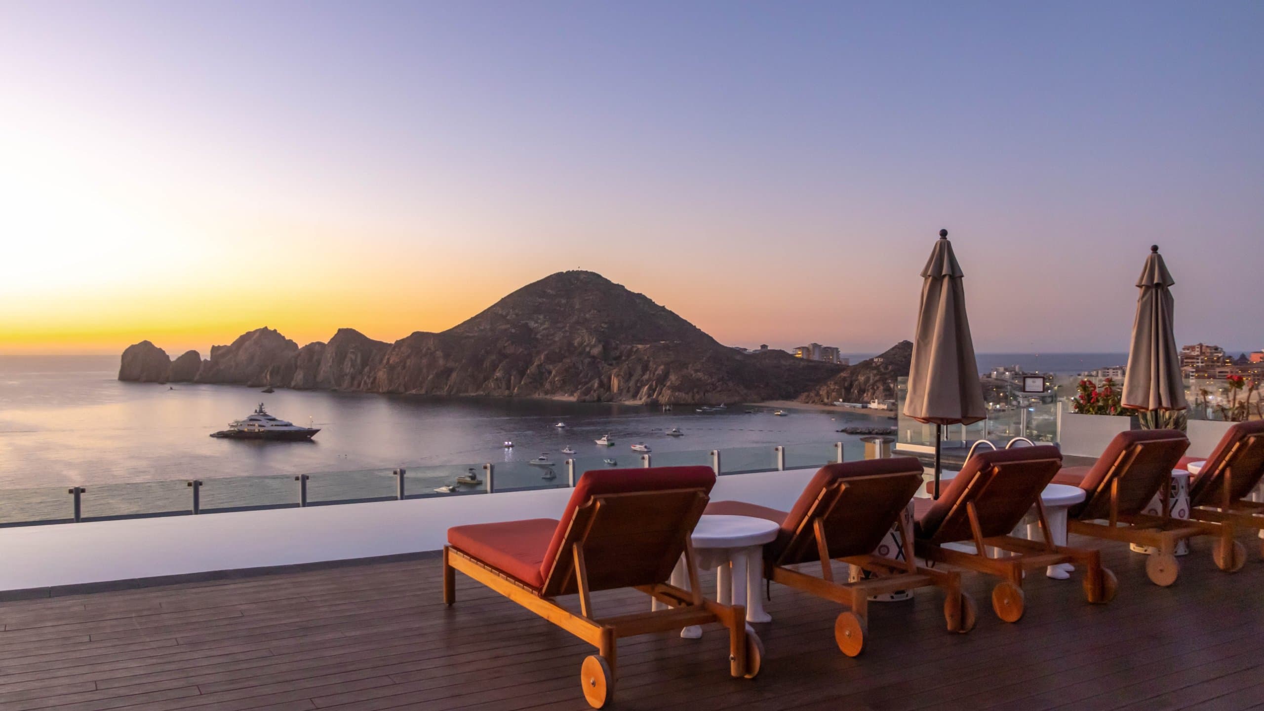Lounge chairs on seating area overlooking the water at a Noble House Hotels & Resorts property
