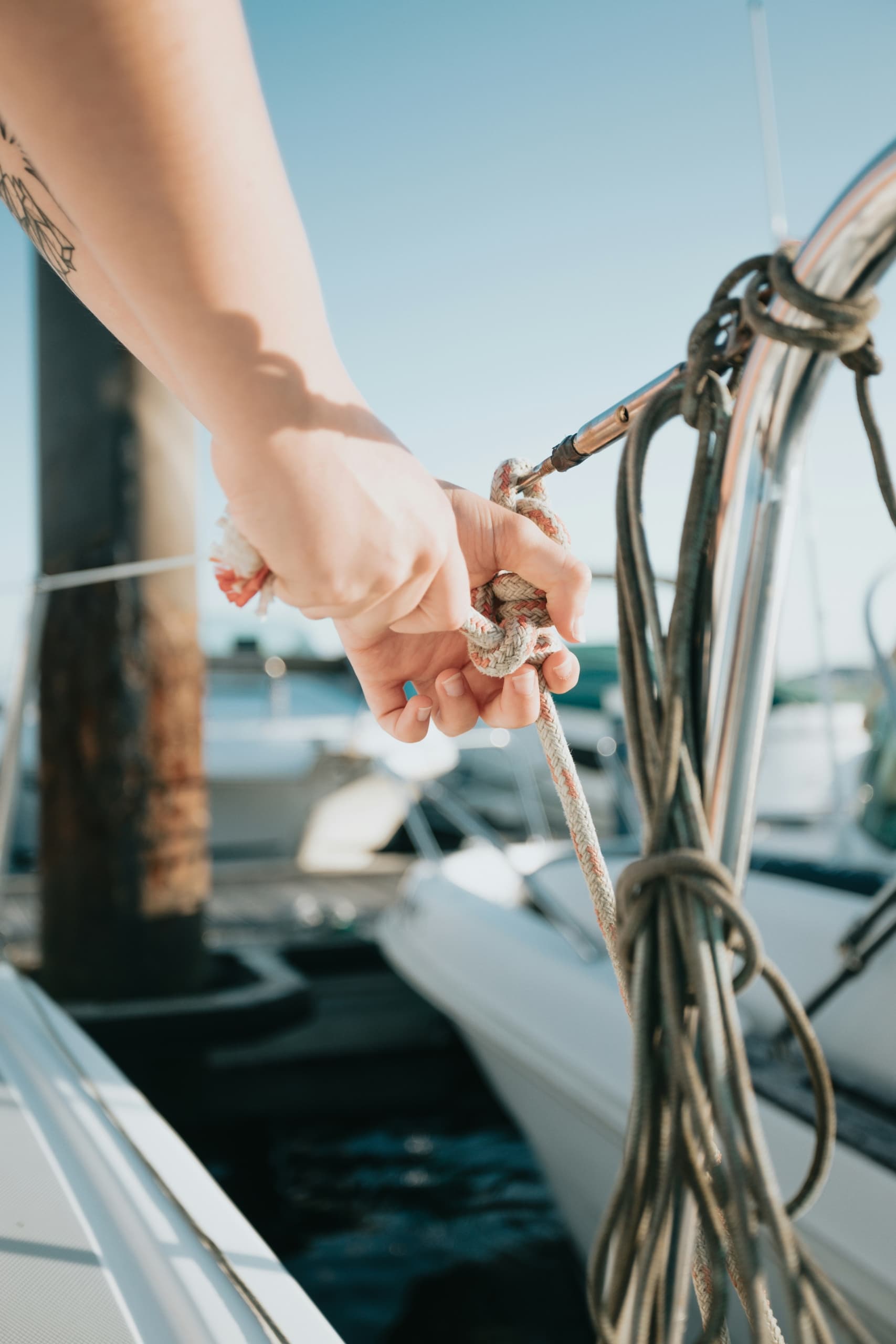 A person tying a knot in a rope securing a boat to the marina