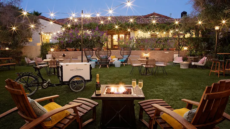 Outdoor green area with seating area next to firepit and lights at a Noble House Hotels & Resorts property