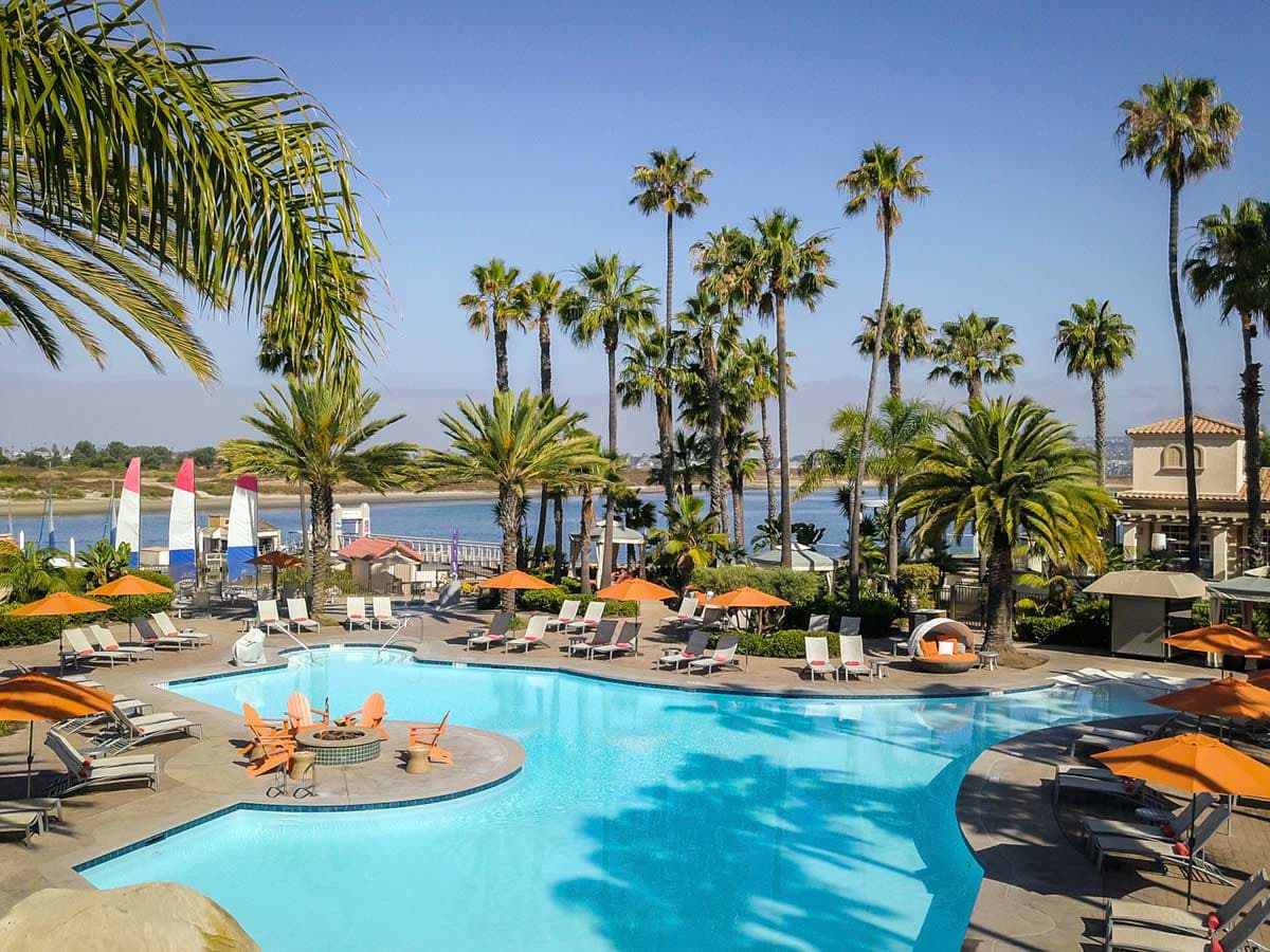 outdoor pool surrounded by palm trees at a Noble House Hotels & Resorts property